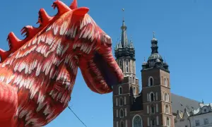 Smok wawelski, znany z atlas obscura krakow, wita turystów na tle Kościoła Mariackiego.