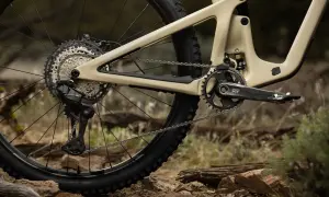 Tylna przerzutka i kaseta napędu rowerowego Shimano Deore LX na piaskowym fullu, gotowe na terenowe wyzwania.
