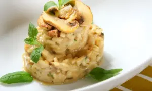 Aromatyczne risotto szafranowe z grzybami, udekorowane świeżą bazylią.