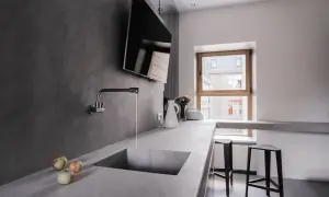 Encimera de cocina moderna con fregadero integrado de microcemento. Grifo cromado y tres manzanas sobre la superficie.