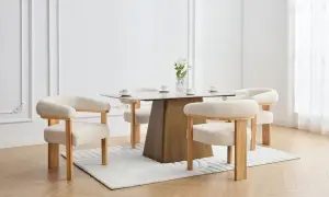En elegant matplats med olika stolar runt ett modernt matbord. En vas med blommor står på bordet.