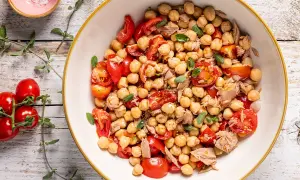 Un'insalata di ceci estiva con pomodorini freschi e tonno, guarnita con erbe aromatiche. Perfetta per un pasto leggero e gustoso.