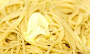 Spaghetti fumanti con una generosa porzione di burro che si scioglie, un classico piatto di pasta in bianco.