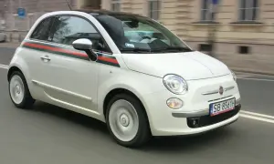 Biały Fiat 500 1.2 z zielono-czerwonym pasem na boku, w ruchu miejskim.