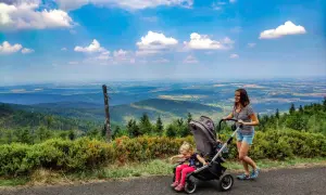 Mama z córką na spacerze, gdzie w góry z wózkiem. Piękny widok na dolinę i chmury.