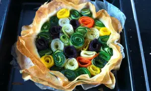Une quiche aux légumes colorés, enroulés en spirales, dans une pâte croustillante.