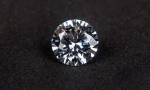 Błyszczący, okrągły, słynny diament o wielu fasetkach, leżący na czarnym, aksamitnym tle.