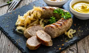 Pyszna biała kiełbasa z grilla, podana z duszonymi cebulkami i musztardą. Idealna na letni obiad.