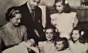 Familjefoto med prinsessan Sibylla och hennes barn. Bilden visar en familj med föräldrar och flera barn, inklusive en bebis. Prinsessan Sibylla bar en mönstrad klänning.