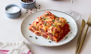 Pyszne cannelloni z mięsem mielonym, zapieczone pod sosem pomidorowym i serem, udekorowane świeżym tymiankiem.