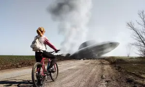 Dziewczyna na rowerze patrzy na lądujący statek kosmiczny, co pokazuje, czym jest cgi. Dym unosi się z obiektu.