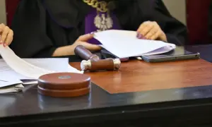 Sędzia w todze przegląda dokumenty, obok młotek i tablet. Może to oznaczać zawieszenie postępowania kpc.