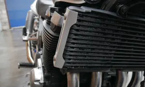 Chłodnica oleju motocykla, część silnika chłodzonego powietrzem, z widocznymi żeberkami i kroplami wody.