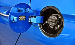 Otwarty wlew paliwa w Toyocie Yaris. Widać klapkę z uchwytem i instrukcją, a także zakrętkę z ostrzeżeniem.