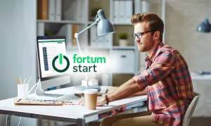 Mężczyzna przy biurku pracuje na komputerze z logo Fortum.