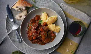 Herzhaftes Spezzatino di manzo mit cremigem Polenta, dazu ein Glas Rotwein und rustikales Brot.