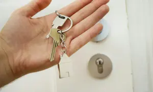 En hand håller nycklar med ett hus som berlock. Dags att byta lås och få nya nycklar till hemmet.