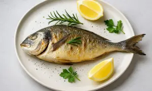 Dorada, czyli dorada królewska, to pyszna ryba na talerzu, ozdobiona cytryną i rozmarynem.