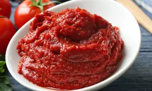Schüssel mit selbstgemachtem Tomatenmark, daneben frische Tomaten.