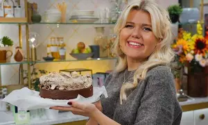Glad kvinna håller upp en läcker kladdkaka variant med fluffig topping.