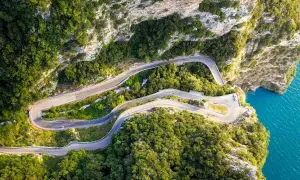 La strada della forra serpeggia tra rocce e vegetazione lussureggiante, con curve mozzafiato a picco sul mare turchese.