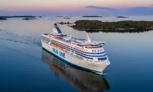 Prom Silja Line płynie przez spokojne morze, tworząc fale. W tle widać wyspy i lasy, a niebo mieni się pastelowymi barwami. Idealna podróż z Tallinna do Helsinek.