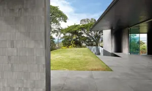 Pareti e pavimenti in gres 2 cm creano un'atmosfera moderna, con piscina a sfioro e scultura gialla in giardino.