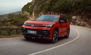 Röd Volkswagen kör på en kurvig väg i bergen. Denna hybridbil kombinerar eldrift med bensinmotor, vilket ger en flexibel körupplevelse.