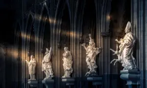 Rzędy rzeźb świętych w katedrze, oświetlone snopami światła. Czy mogę iść do komunii?