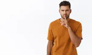 Uomo con dito sulle labbra, sguardo intenso. Un chiaro messaggio: quando un uomo ti dice lasciami in pace, è meglio ascoltare.