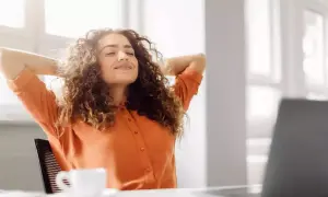 Femme souriante, mains derrière la tête, profitant d'une pause. Son retour congé maternité obligation employeur semble bien se passer.