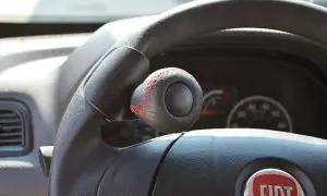 Pomello volante in pelle nera con cuciture rosse, un accessorio che rispetta la normativa per una guida sicura e personalizzata.