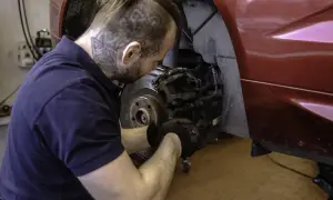 Mechanik w rękawiczkach naprawia hamulce w czerwonym Volvo. Dbałość o szczegóły zapewnia długą gwarancję.
