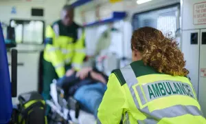 Personale sanitario assiste paziente su barella in ambulanza, garantendo il trasporto sicuro secondo la legge 104.