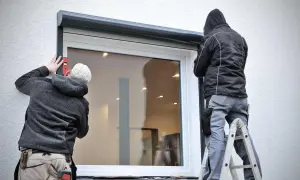 Zwei Handwerker führen die vorbaurollladen montage durch. Einer richtet mit Wasserwaage aus, der andere steht auf Leiter.