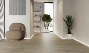Ljus hall med klinker som ser ut som trägolv. En unik fåtölj och gröna växter skapar en inbjudande atmosfär.