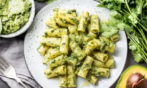 Rigatoni-Nudeln mit cremigem Avocado-Pesto, garniert mit frischem Koriander und Basilikum.