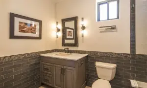 Bathroom vanity with a sink, mirror, and two wall sconces. The sconce height from floor is about 4 feet, illuminating the artwork and vanity.