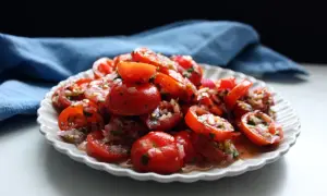En härlig tomat sallad med rödlök och örter, serverad på en vit, mönstrad tallrik.