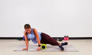 Donna usa un foam roller per alleviare la bandelletta ileotibiale. Soluzioni per il recupero muscolare.
