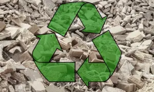 Símbolo de reciclaje verde sobre un montón de escombros de hormigón reciclado.