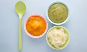 Drei Schälchen mit Brei (orange, grün, weiß) und ein Löffel. Ideal für die Beikosteinführung: ab wann Obstbrei Baby?