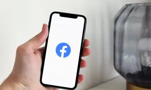 Dłoń trzyma smartfon z logo Facebooka. Dowiedz się, jak wstawić ogłoszenie na FB, by dotrzeć do szerokiego grona odbiorców.