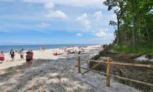 Słoneczny dzień na plaży w Karwieńskich Błotach. Ludzie odpoczywają na piasku, a morze wzywa do kąpieli.