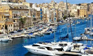 Malta historia: malowniczy port pełen jachtów, z zabytkową zabudową w tle.