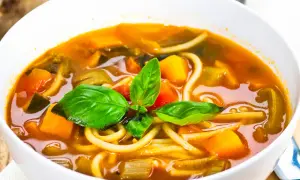 Una ciotola di pasta con i tenerumi, ricca di verdure colorate e basilico fresco. Un piatto confortante e salutare.