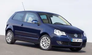 Granatowy Volkswagen Polo 2003, trzydrzwiowy, z jasnym wnętrzem, stoi na szarej nawierzchni.