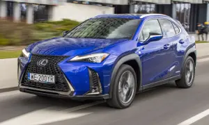 Błękitny Lexus UX 200 w ruchu miejskim, z widocznym grillem i reflektorami.