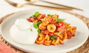 Pasta mit Salsiccia-Sauce und Burrata auf einem Teller.