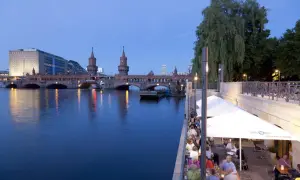 Abendstimmung an den Rivo SpreeTerrassen: Gäste genießen das Ambiente am Wasser mit Blick auf die Oberbaumbrücke.
